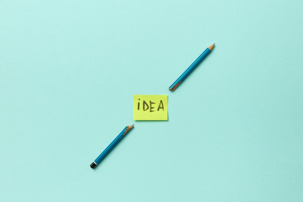 Conceptual photo of a broken pencil with a sticky note labeled 'idea' on a blue background.