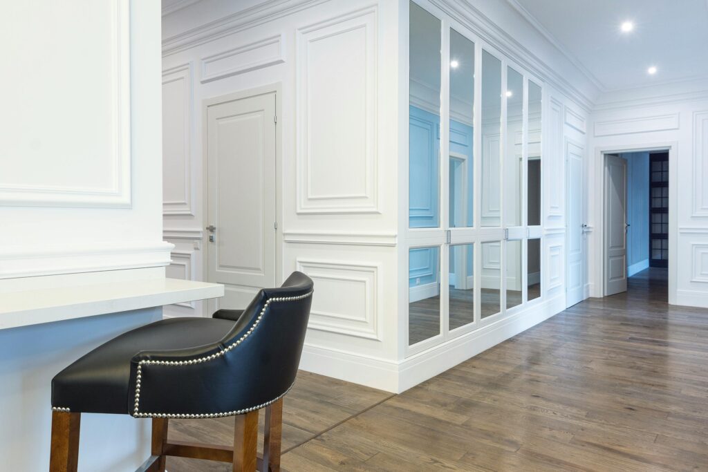 Spacious contemporary interior features white panel walls, mirrored doors, and elegant wooden flooring.